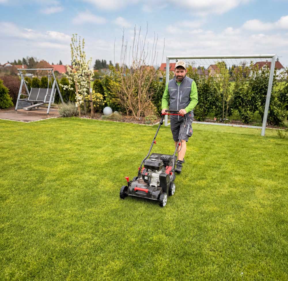 Gartenkonzepte-Mitarbeiter mäht den Rasen in einem gepflegten Privatgarten in Pirna – professionelle Grün- und Rasenpflege vor Ort