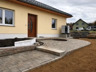 Neu gepflasterte Hauseinfahrt mit Rundelement vor einem Einfamilienhaus im Neubau – Außenanlage und Gartengestaltung