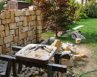 Handwerklicher Bau einer Natursteinmauer mit Werkzeug und Steinmaterial im Garten – Gartengestaltung Dresden