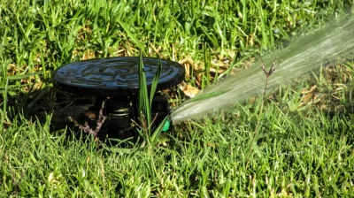 Versenkbarer Rasensprinkler in Betrieb bei der automatischen Bewässerung einer Grasfläche – Bewässerungssystem