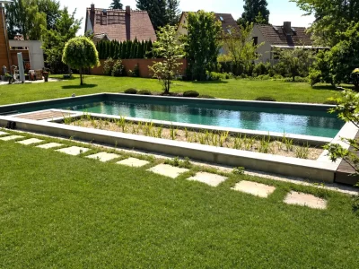 Moderner Schwimmteich mit Pflanzzone und Trittsteinplatten in einem gepflegten Privatgarten mit sattem Rasen